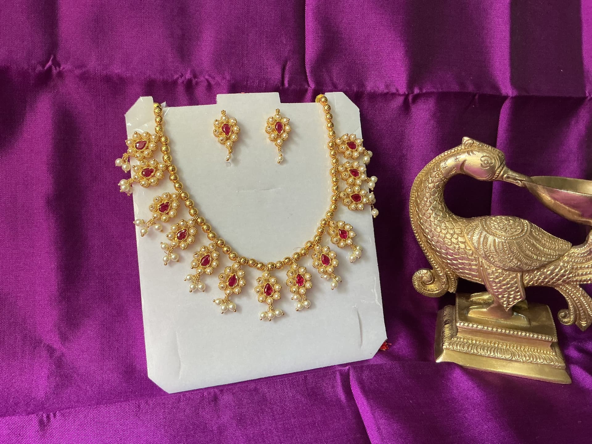 A gold necklace and matching earrings set with rubies and pearls